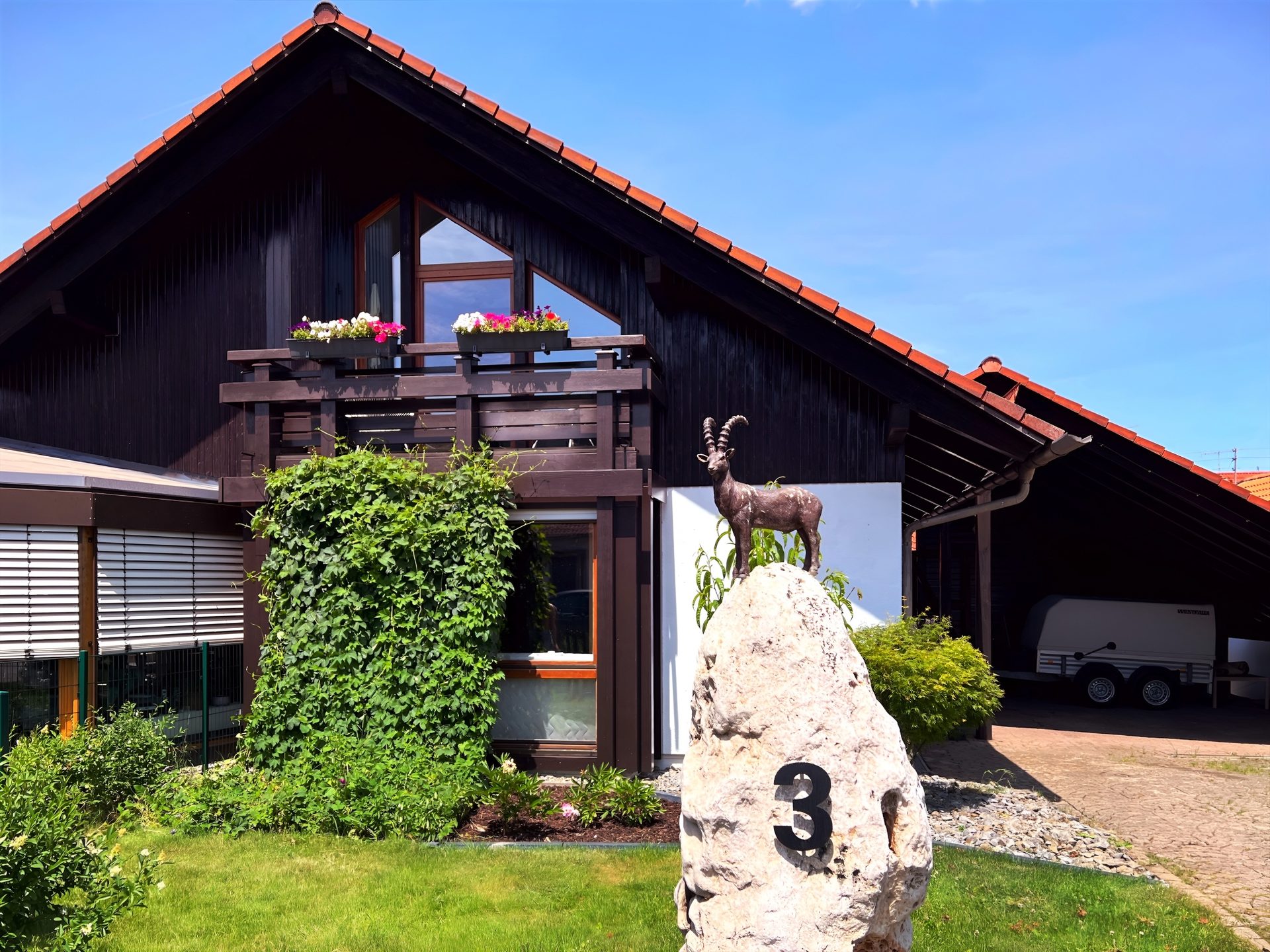 Unser Holzhaus in Neuhausen ob Eck mit Balkon und der Steinbock-Figur im Vorgarten