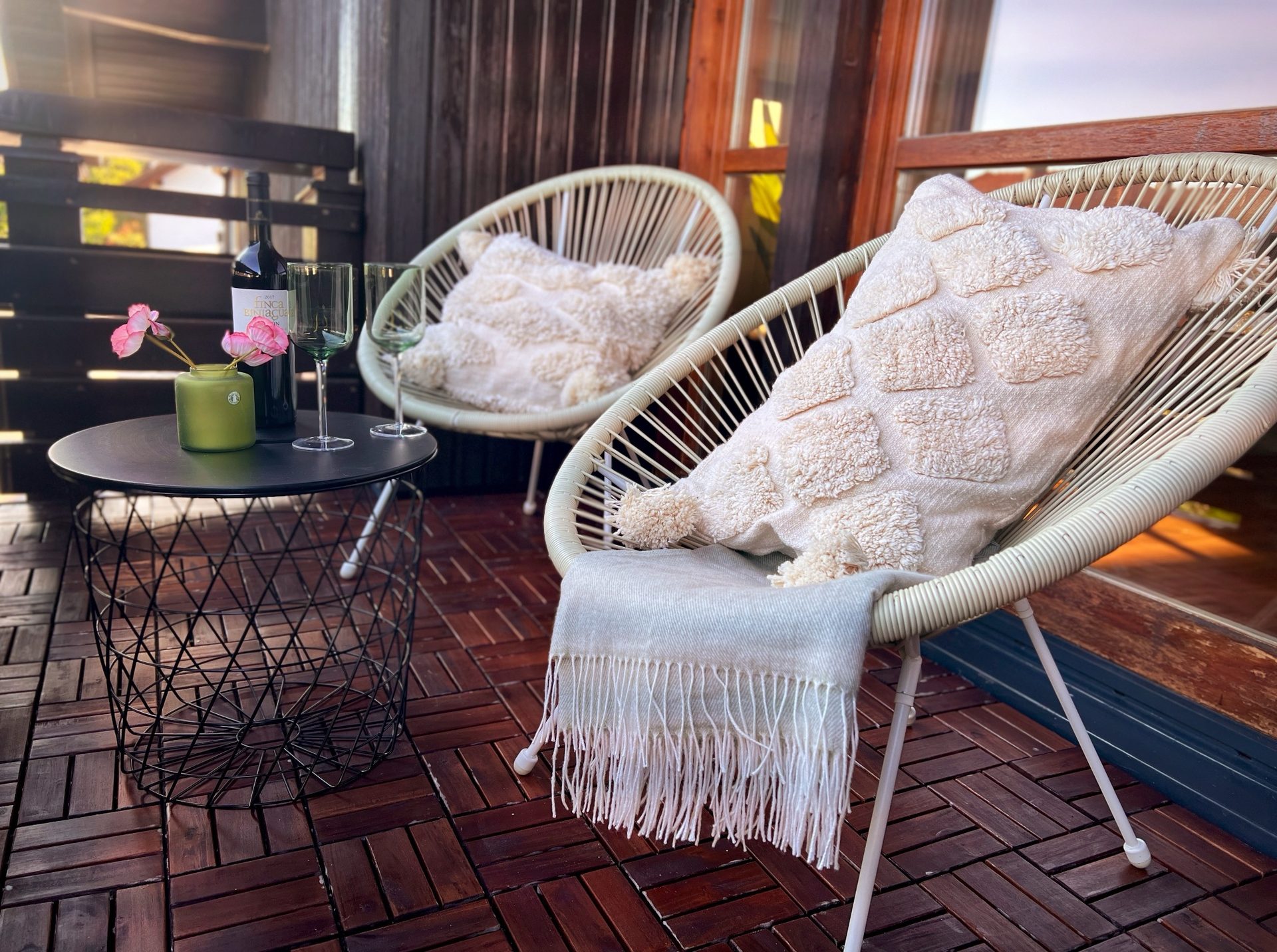 Balkon mit zwei Sesseln, Kissen und kleinem Tisch in der Abendsonne