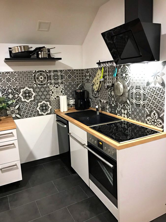 Küchenzeile mit schwarzem Dunstabzug und Mosaikfliesen