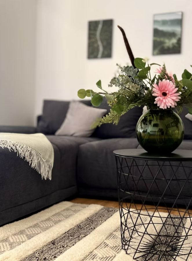Couch mit Kissen, Beistelltisch und Blumen im Wohnbereich